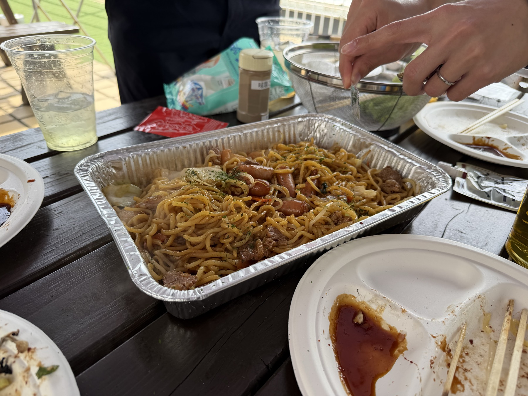 户外木桌上铝箔盒里的炒面。