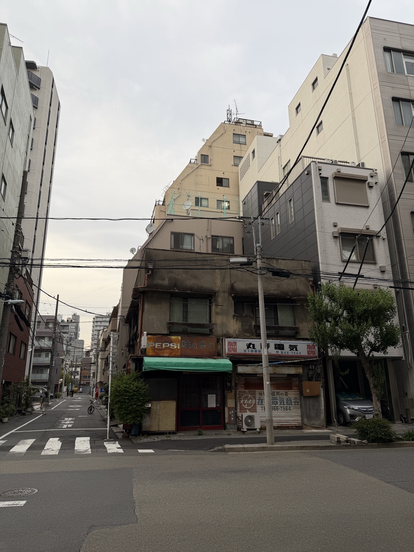 阴天里的东京旧建筑、架空电线和街角。